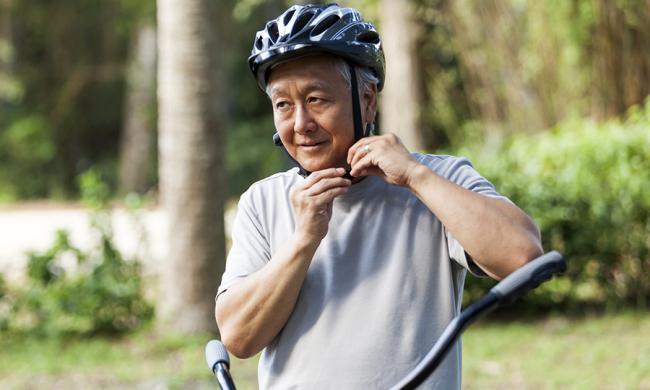 Hombre mayor se abrocha su casco.