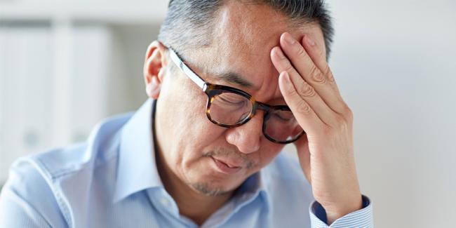 Imagen de un hombre con la mano en la frente por el dolor.