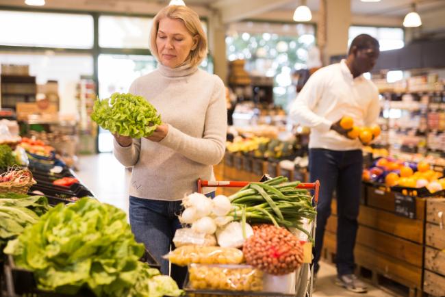 Fotografía de una mujer de mediana edad comprando verduras frescas.