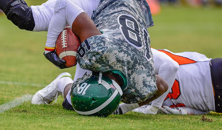 Imagen de un jugador de fútbol americano de secundaria cayendo de cabeza.