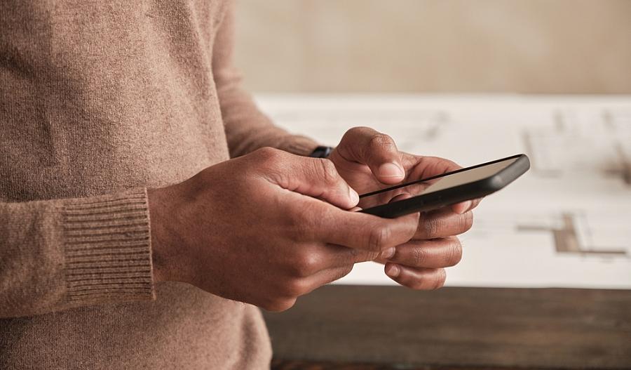 Una fotografía muestra las manos de un hombre usando su teléfono celular inteligente